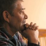 man with dementia staring off into the distance with hands cupped to his chin